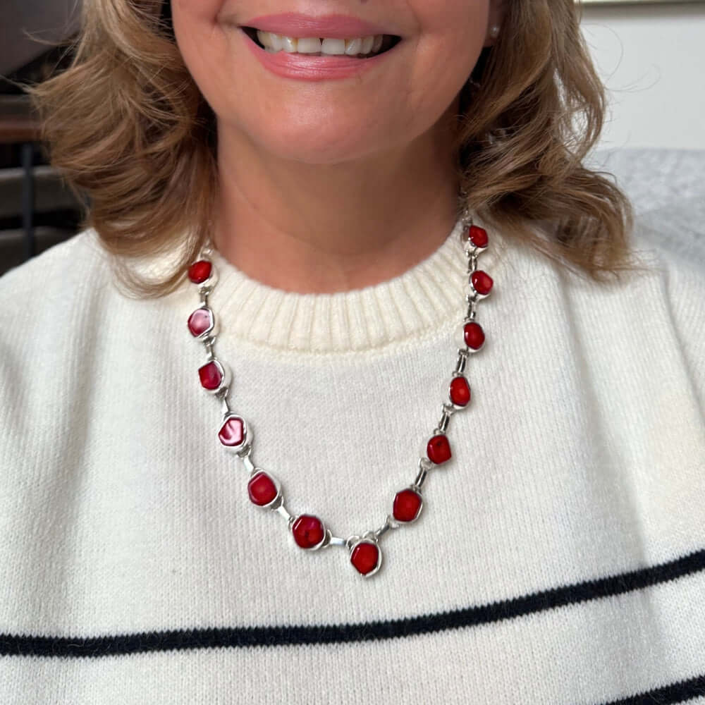 Person wearing a red coral silver necklace with a white sweater