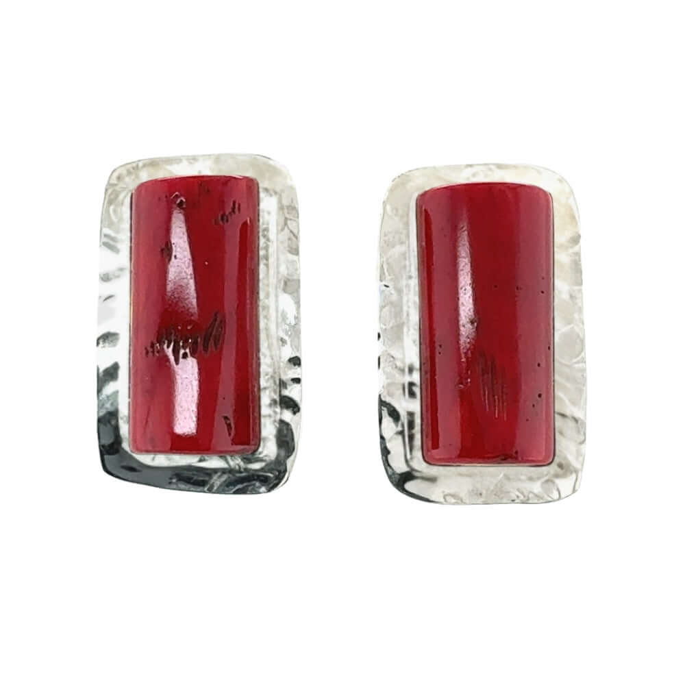 Pair of earrings with red central coral and textured silver frames on a white background