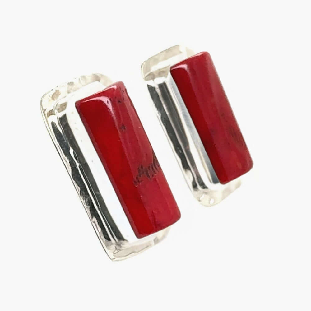Pair of earrings with red cylindrical coral and silver accents on a white background