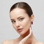 Woman wearing a red coral earring on a gray background