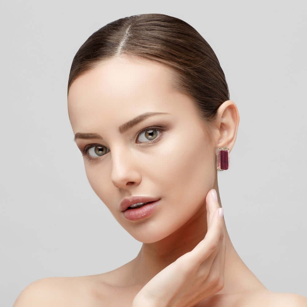 Woman wearing a red coral earring on a gray background