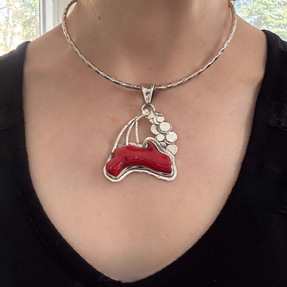 Necklace with a red coral worn by a person