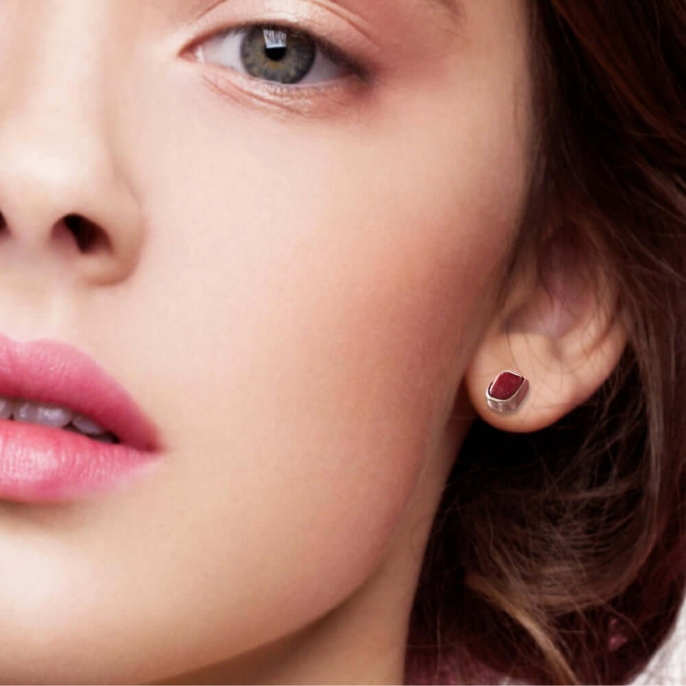 Close-up of a woman wearing a red coral silver earring.