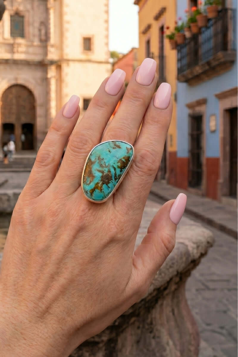 Hand wearing a Sonoran Turquoise silver ring with a Mexican town as background
