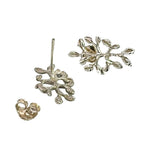 A pair of silver stud earrings with textured, organic leaf-like branches, shown on a plain white background with one earring displaying the front design and the other showing the post and butterfly back.