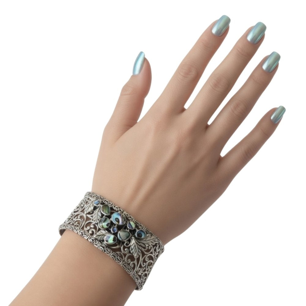Decorative Taxco silver bracelet with abalone details on a hand with a white background