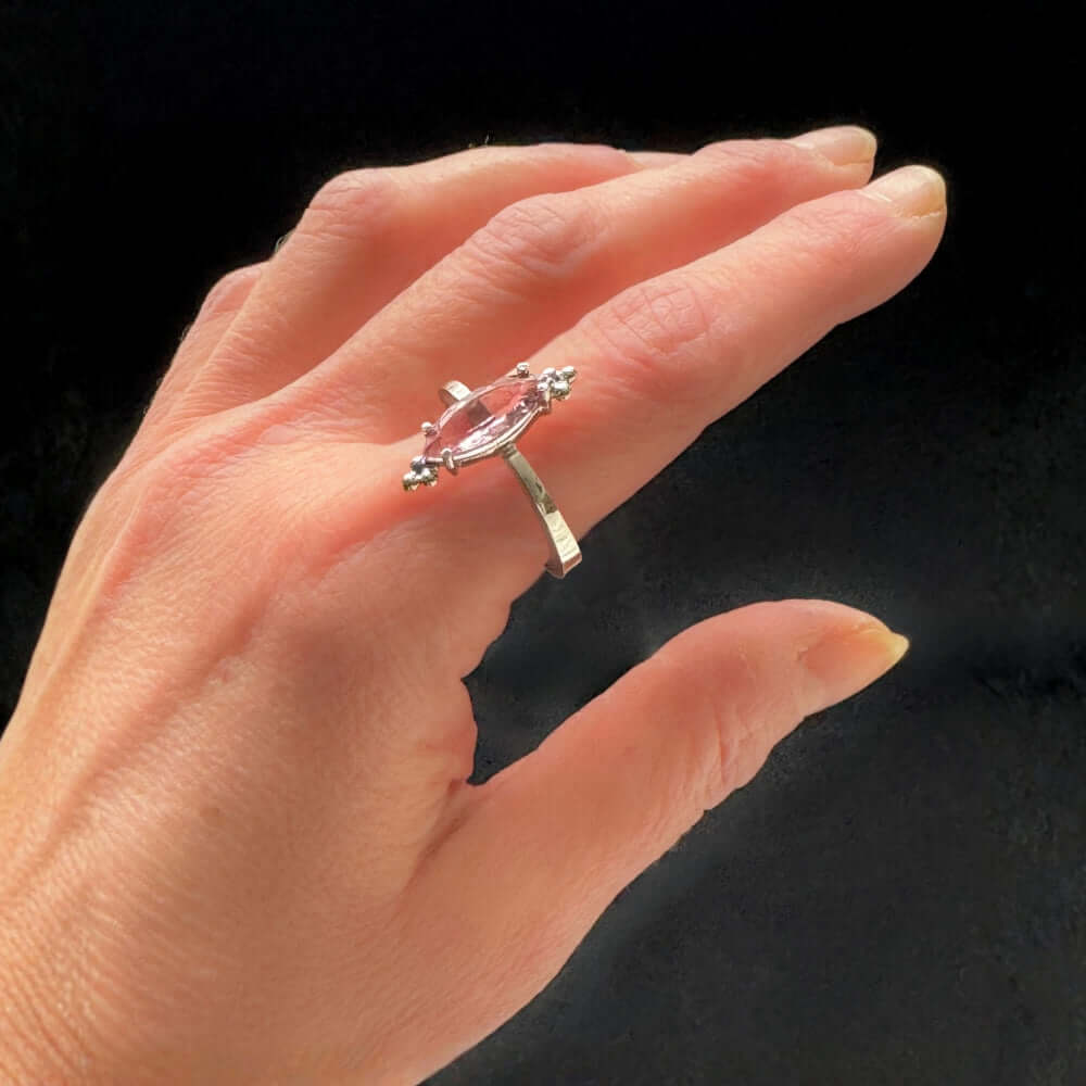Hand wearing a Taxco silver ring with a pink gemstone on a black background
