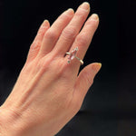 Hand wearing a ring with a pink gemstone on a black background