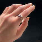 Hand wearing a silver ring with a pink gemstone on a black background
