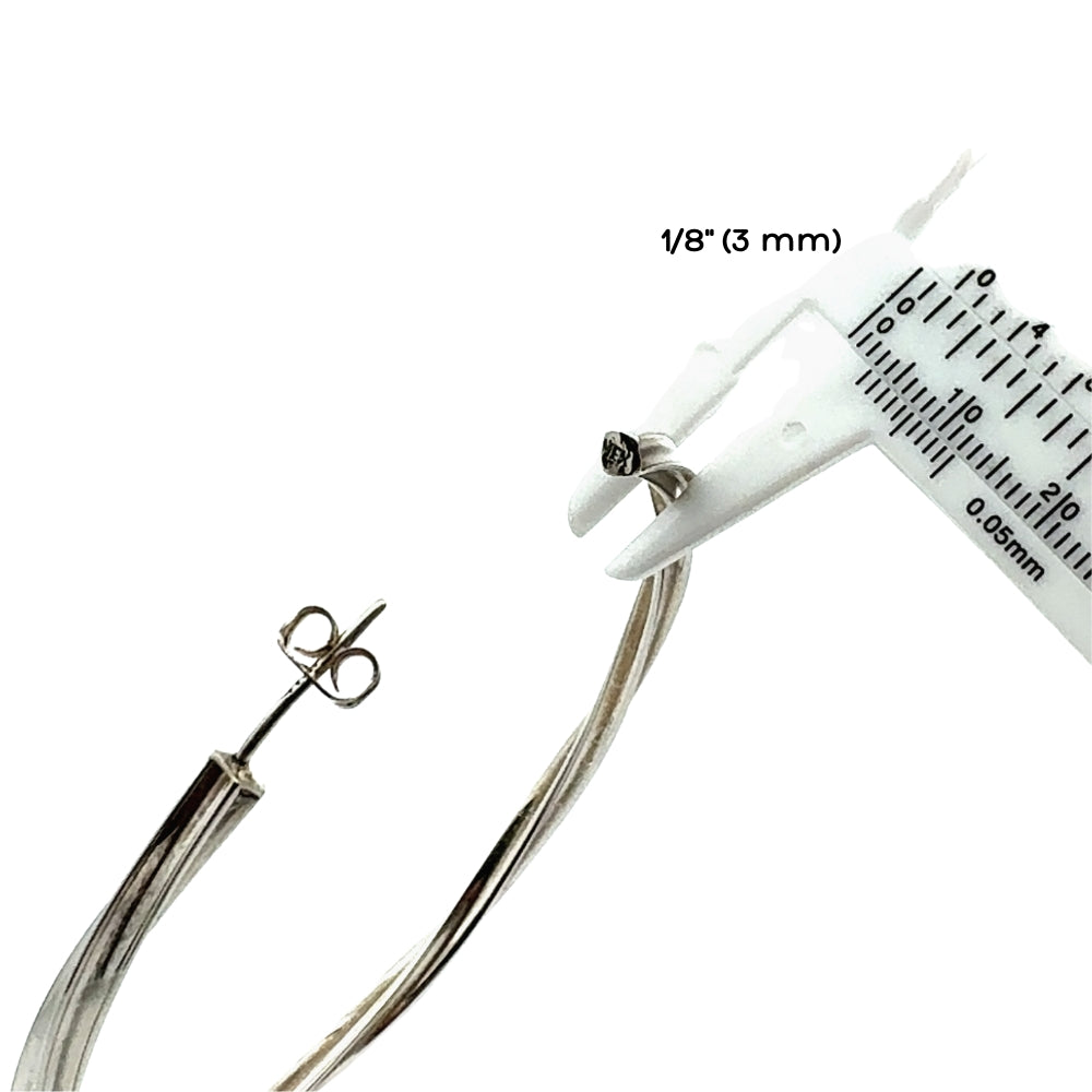 Silver hoop earring with a measuring tool indicating its thickness on a white background