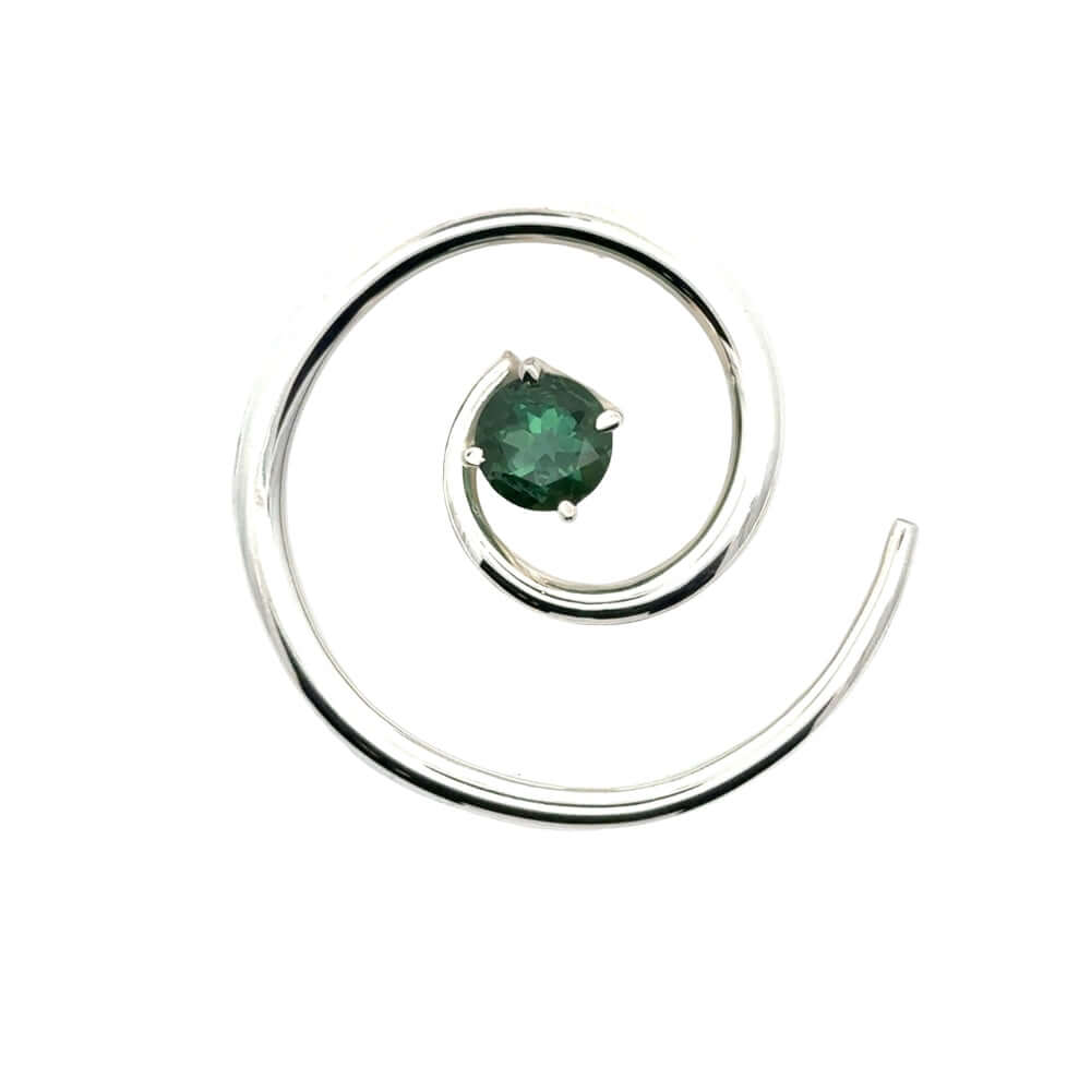 Overhead view of a circular Taxco silver spiral pendant with a green tourmaline center