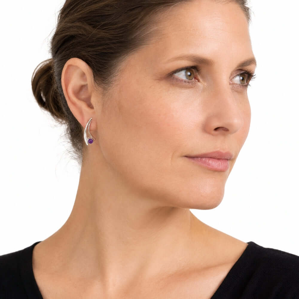 Elegant silver arc earrings with amethyst shown on a model to illustrate their scale and daily wear appeal.