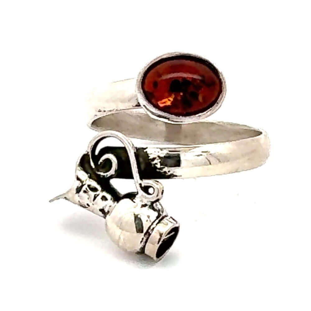 Front view of a bypass 950 silver ring featuring a traditional pitcher motif and an oval amber stone.