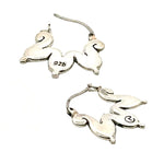 Side view of the sterling silver hoops by Stuart Alarcón emphasizing the unique silhouette.