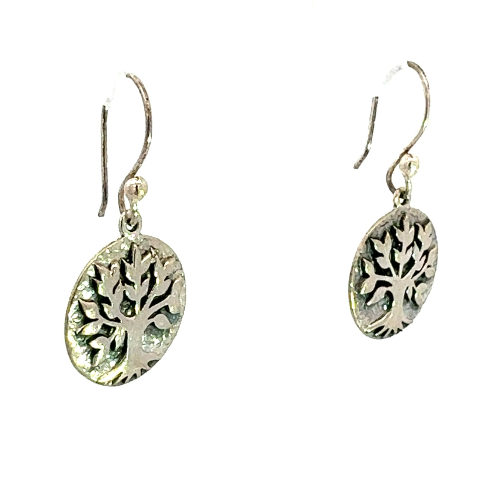 Angled view of authentic Mexican silver earrings featuring a textured tree of life design on a circular disc