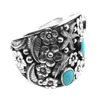 Side view of the wide silver cuff showing hand-carved botanical details