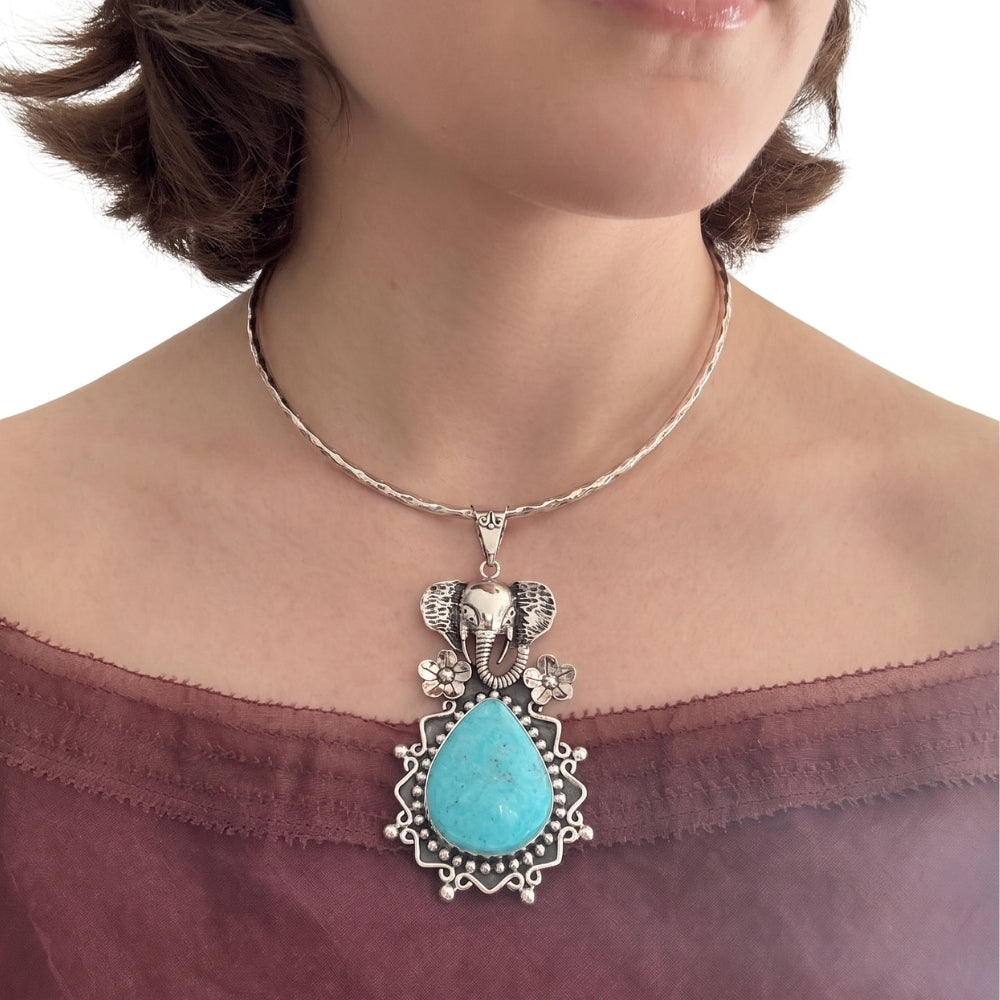 Large sterling silver elephant turquoise pendant styled on a solid silver collar necklace worn against an aubergine top.
