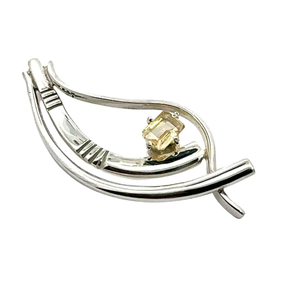 Angled view of an artisan silver pendant highlighting the hand-detailed textures and fluid design.