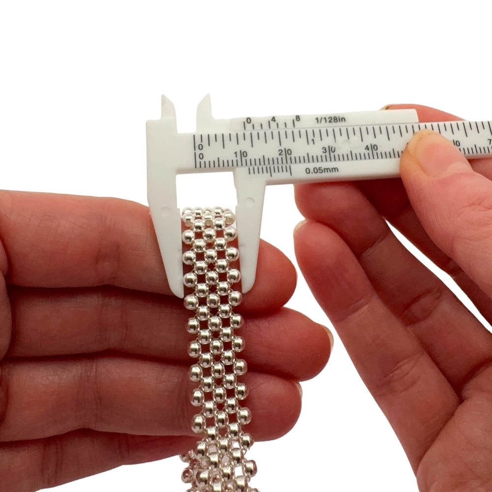 Taxco silver beaded bracelet being measured with a vernier caliper on a white background