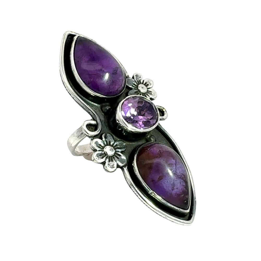 Side angle view showcasing the smooth and faceted bezel settings with the detailed botanical carvings of the artisan long ring.