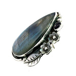 Side angle view showcasing the smooth bezel settings and detailed botanical carvings of the artisan long ring.