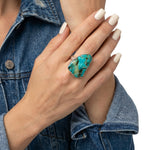 Close-up view of the artisan raw turquoise statement ring worn on a hand, illustrating its bold scale and powerful presence against the skin.