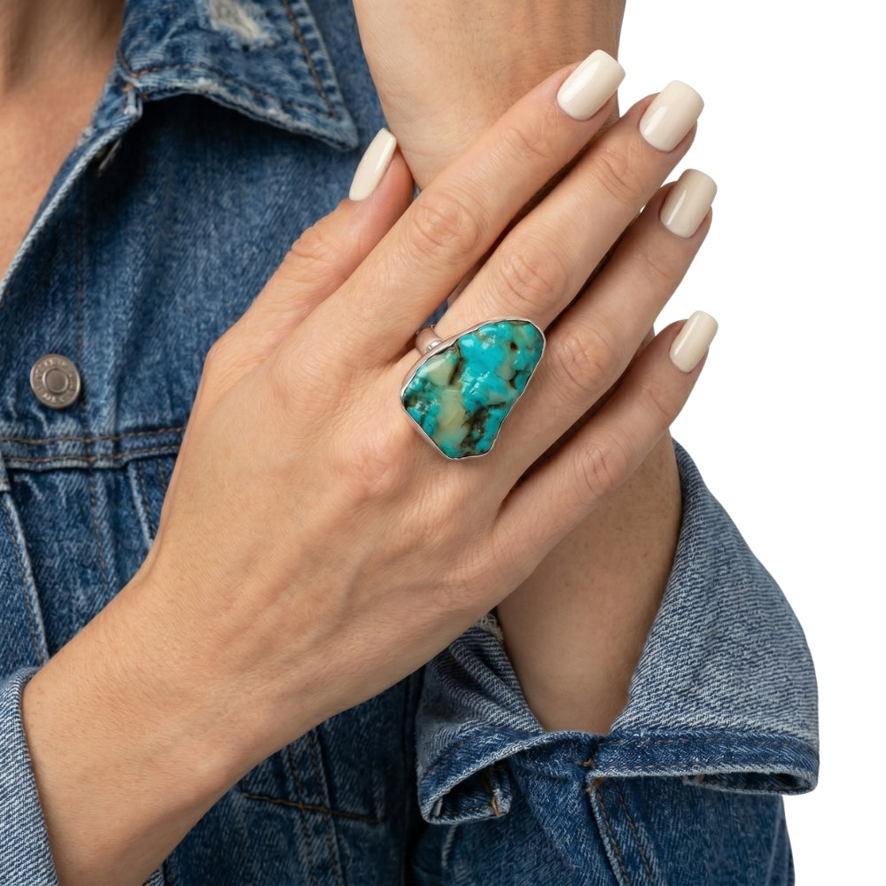 Close-up view of the artisan raw turquoise statement ring worn on a hand, illustrating its bold scale and powerful presence against the skin.