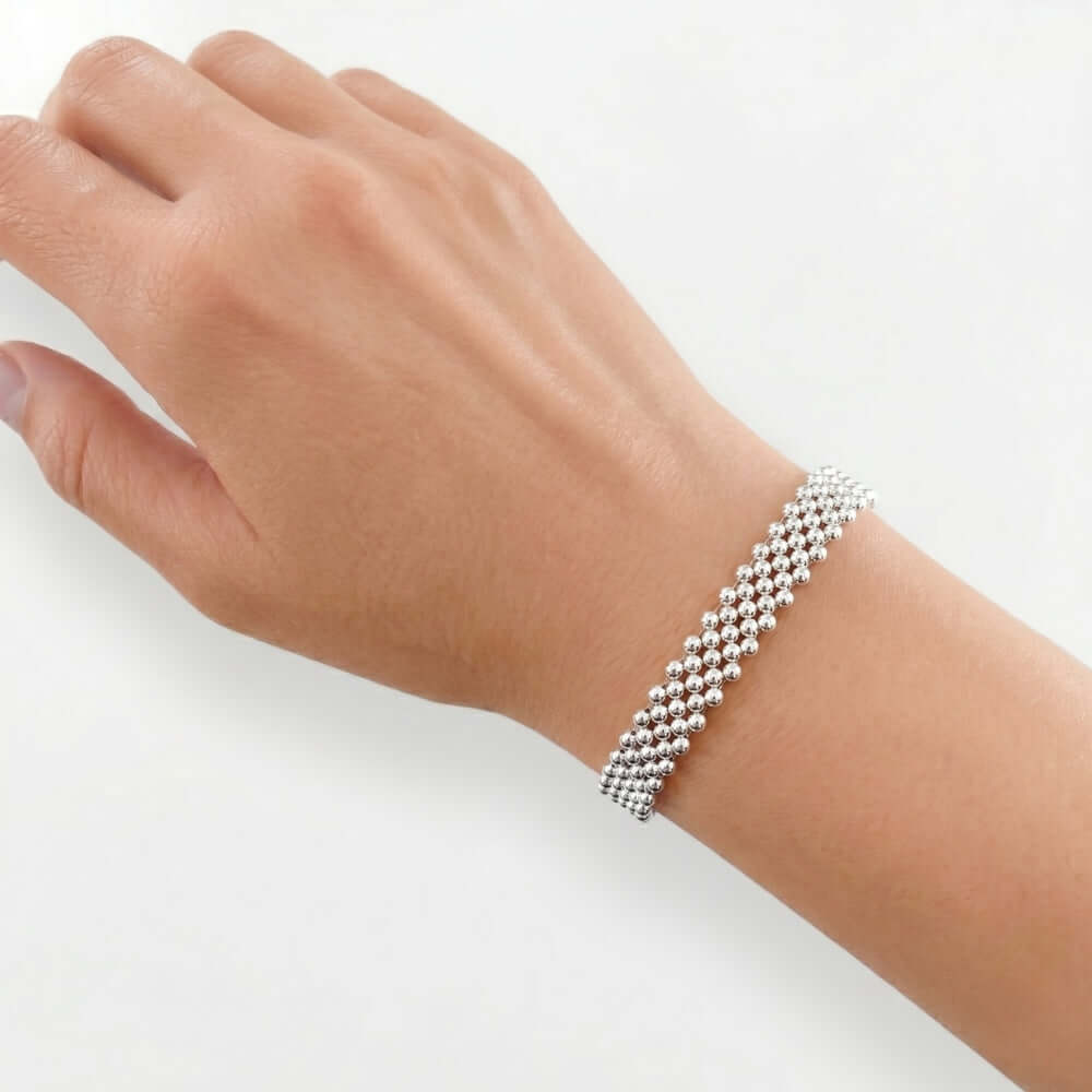The artisan five-strand silver beaded bracelet worn on a wrist, showcasing its bold daily scale and fluid drape.