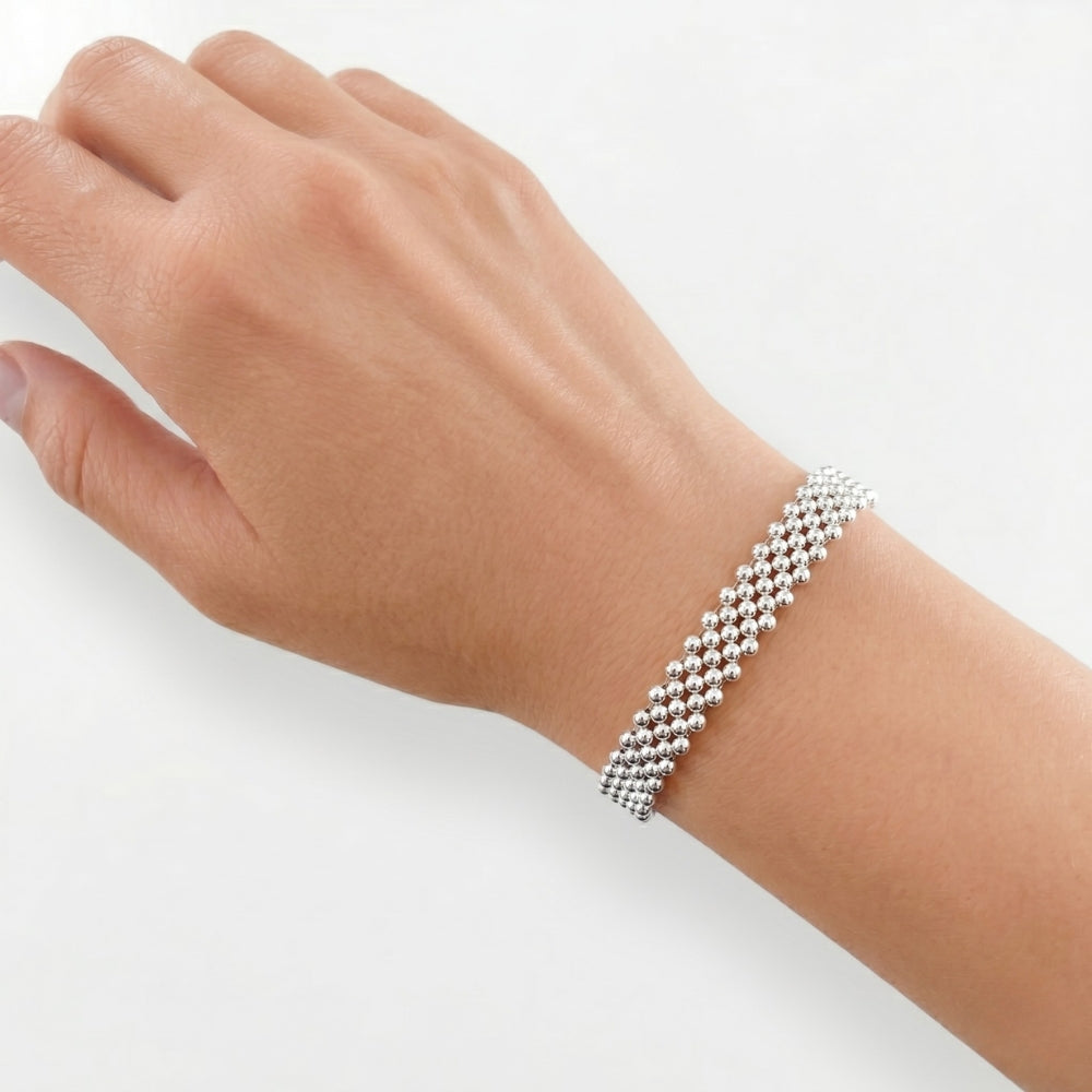 The artisan five-strand silver beaded bracelet worn on a wrist, showcasing its bold daily scale and fluid drape.