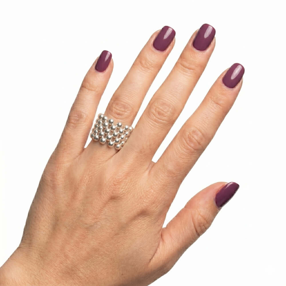 The artisan five-row silver beaded stretch ring worn on a hand, illustrating its wide scale, liquid shine, and knuckle-friendly fit.