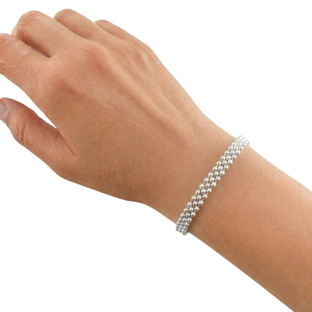 The artisan triple-strand silver bracelet worn on a wrist, showcasing its elegant daily scale and fluid drape.