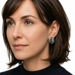 Close-up of a woman wearing a Taxco silver earring on a white background