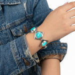 Close-up view of the artisan Western silver turquoise bracelet worn on a wrist, illustrating its elegant drape and reflective shine against the skin.