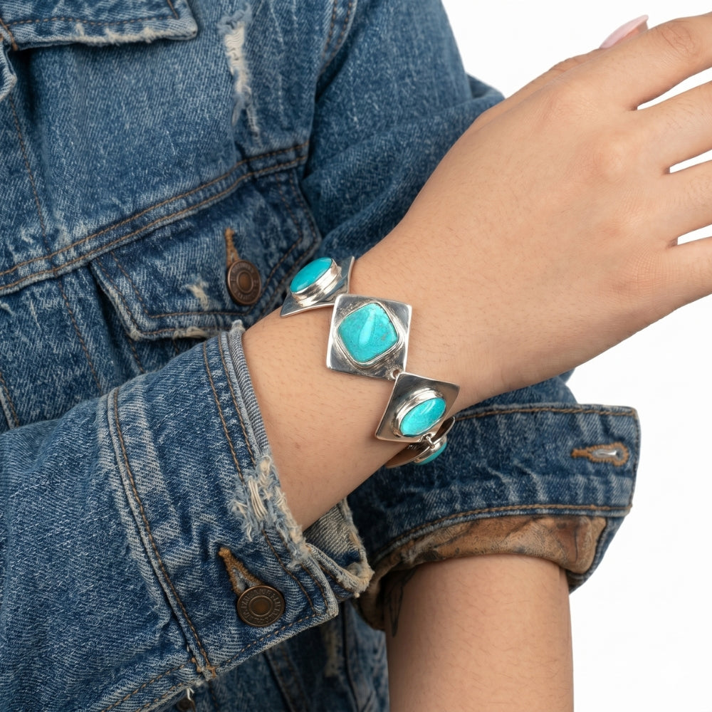 Close-up view of the artisan Western silver turquoise bracelet worn on a wrist, illustrating its elegant drape and reflective shine against the skin.