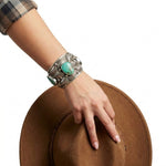 Close-up view of the artisan wide western silver cuff worn on a wrist, illustrating its bold scale and high-contrast finish.