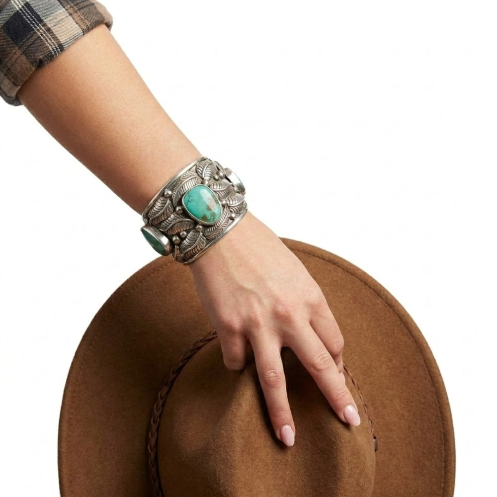 Close-up view of the artisan wide western silver cuff worn on a wrist, illustrating its bold scale and high-contrast finish.