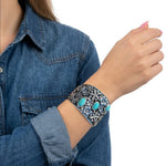 Close-up view of the artisan wide western silver cuff worn on a wrist, illustrating its bold scale and high-contrast finish.