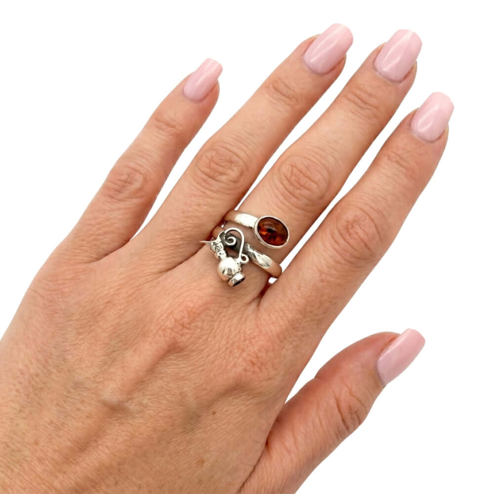 High-purity silver pitcher ring with amber shown on a hand to illustrate its scale and daily wear appeal.