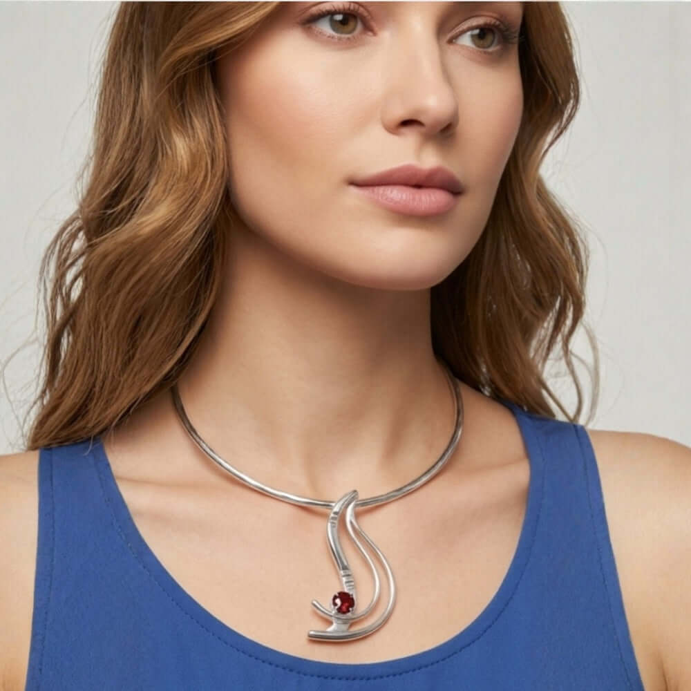 A woman wearing an elegant handmade silver and garnet pendant on a silver choker