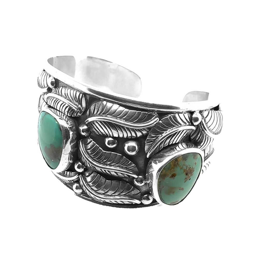 Side perspective showcasing the hand-carved botanical leaves and secure, smooth bezel settings of the turquoise stones.