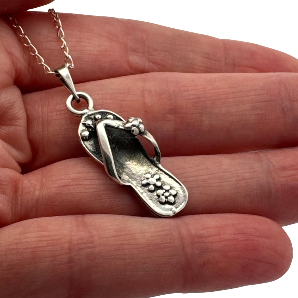 Small silver chancla flip-flop charm held in hand to show actual size