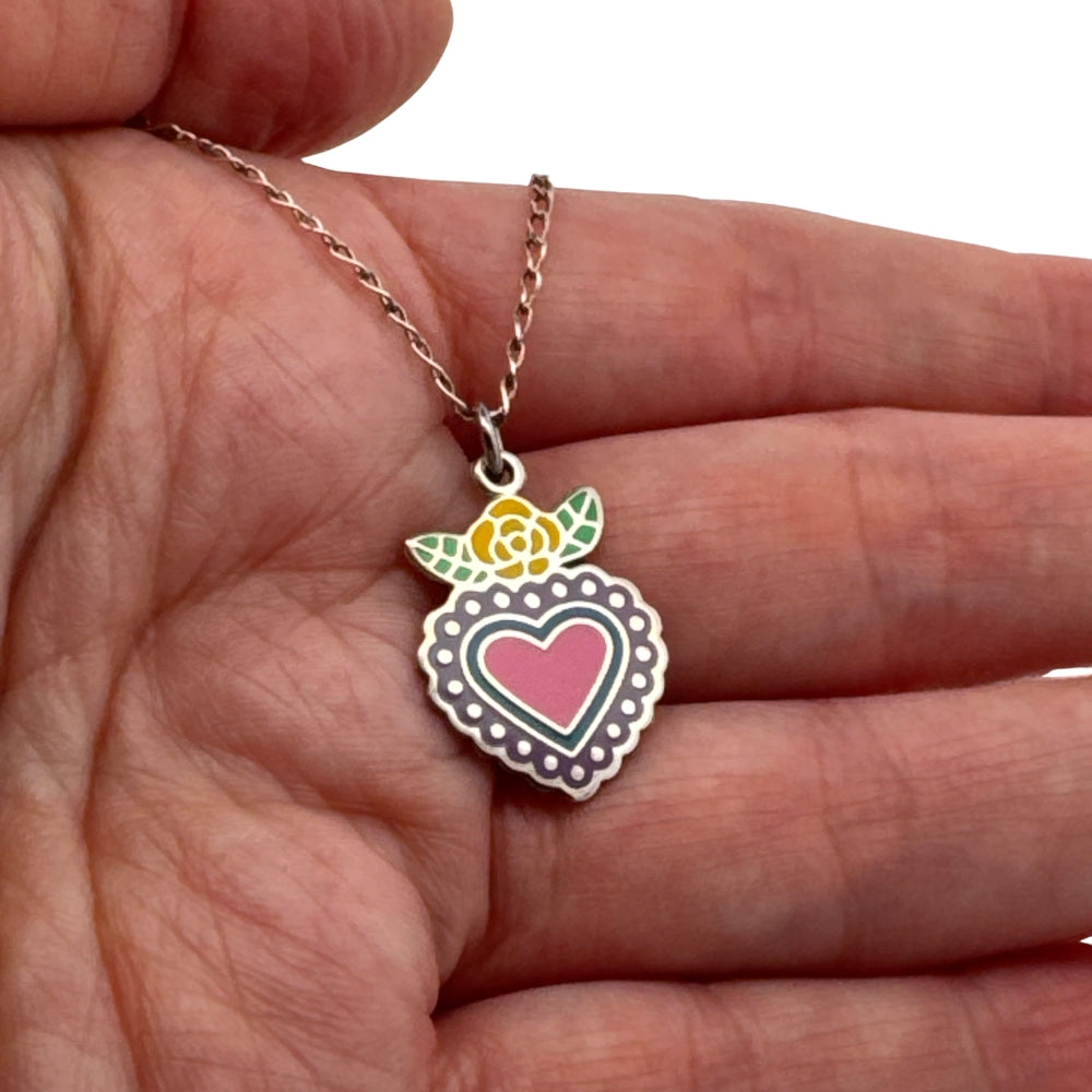 Small silver enamel Mexican heart charm with rose held in hand to show actual size