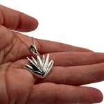 Small silver maguey agave charm held in hand to show actual size