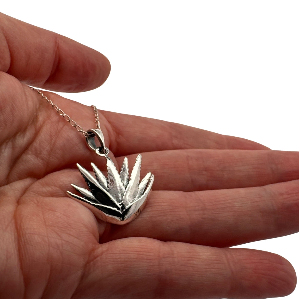 Small silver maguey agave charm held in hand to show actual size