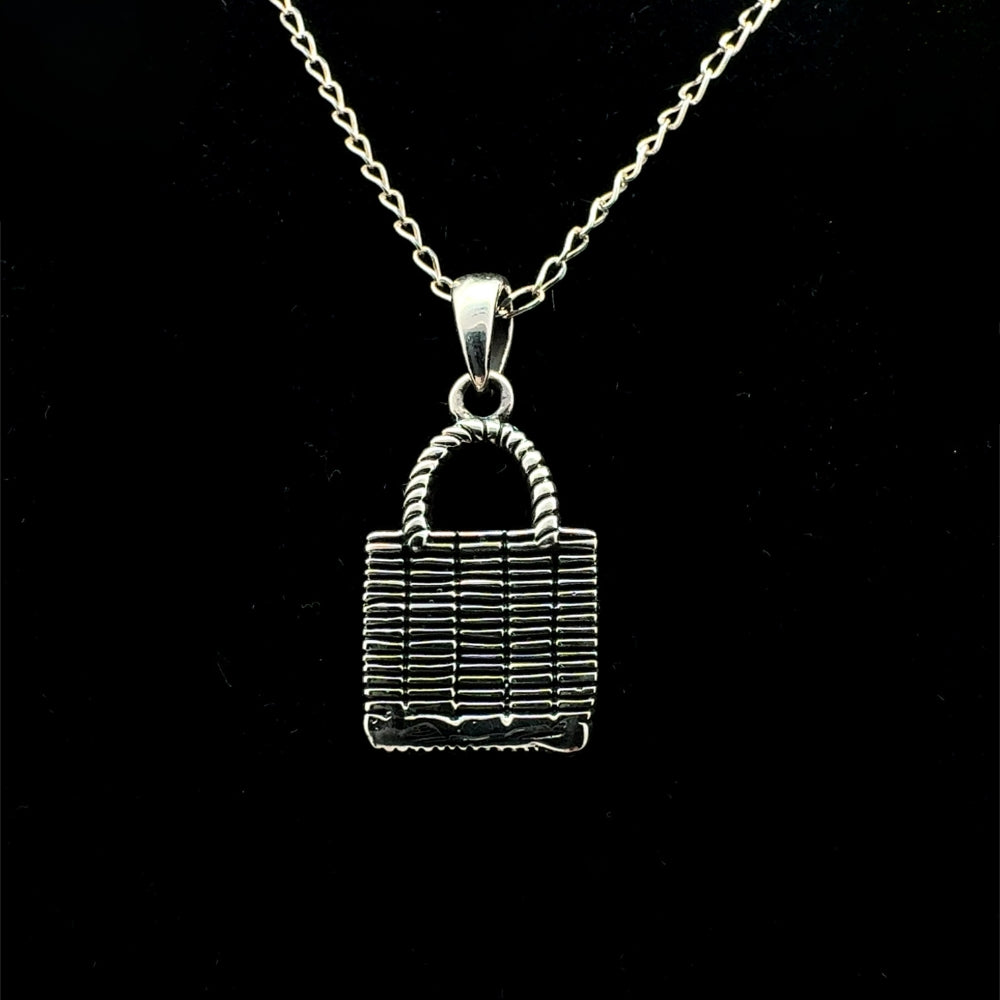 Sterling silver woven market bag pendant necklace with handle, black background