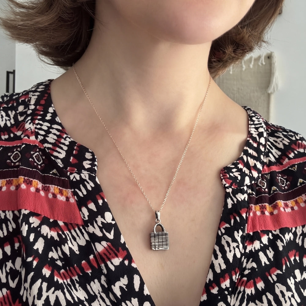 Woman wearing a sterling silver woven market bag pendant necklace