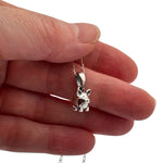 Small silver pig charm pendant held between fingers to show actual size