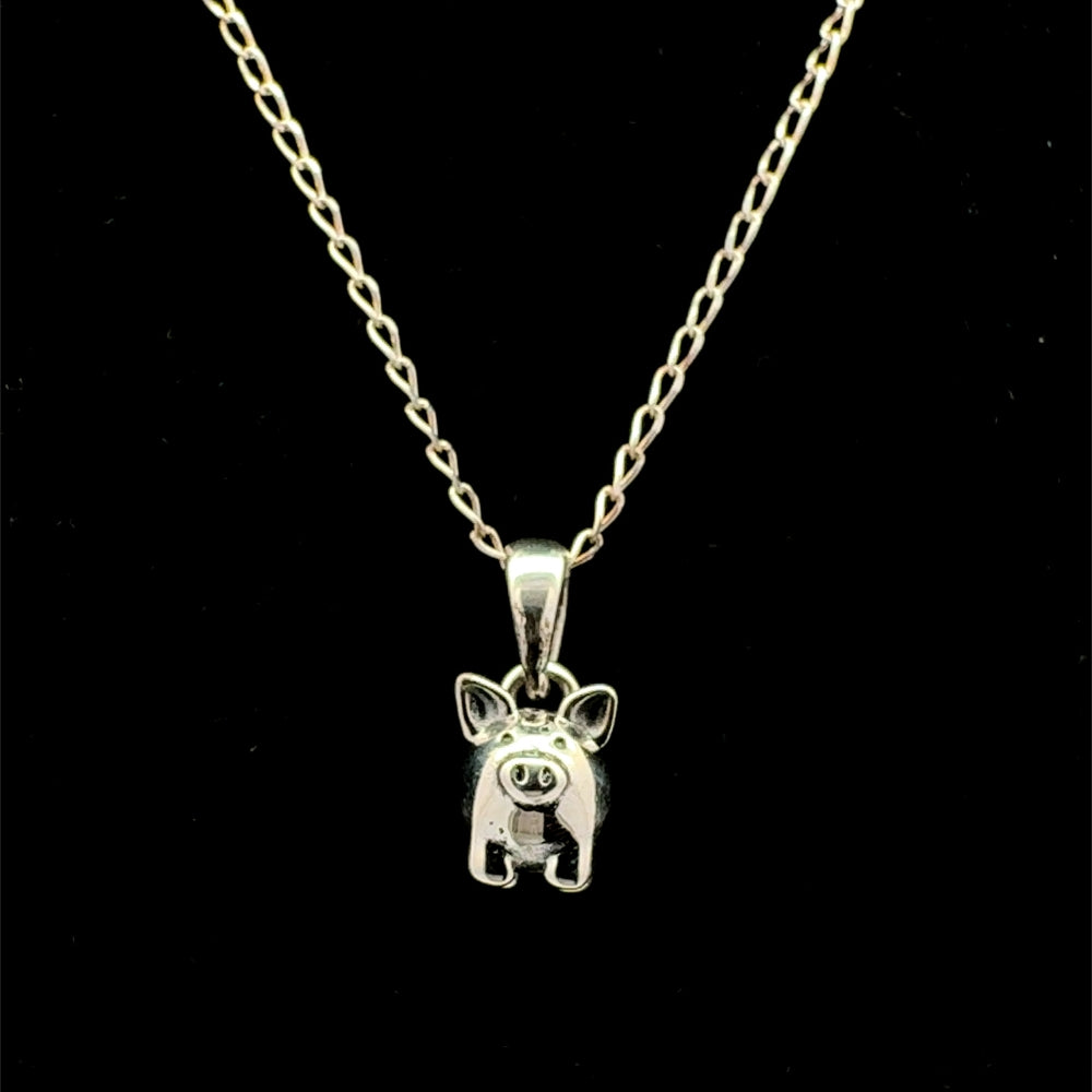 Sterling silver pig pendant necklace with cable chain on black background