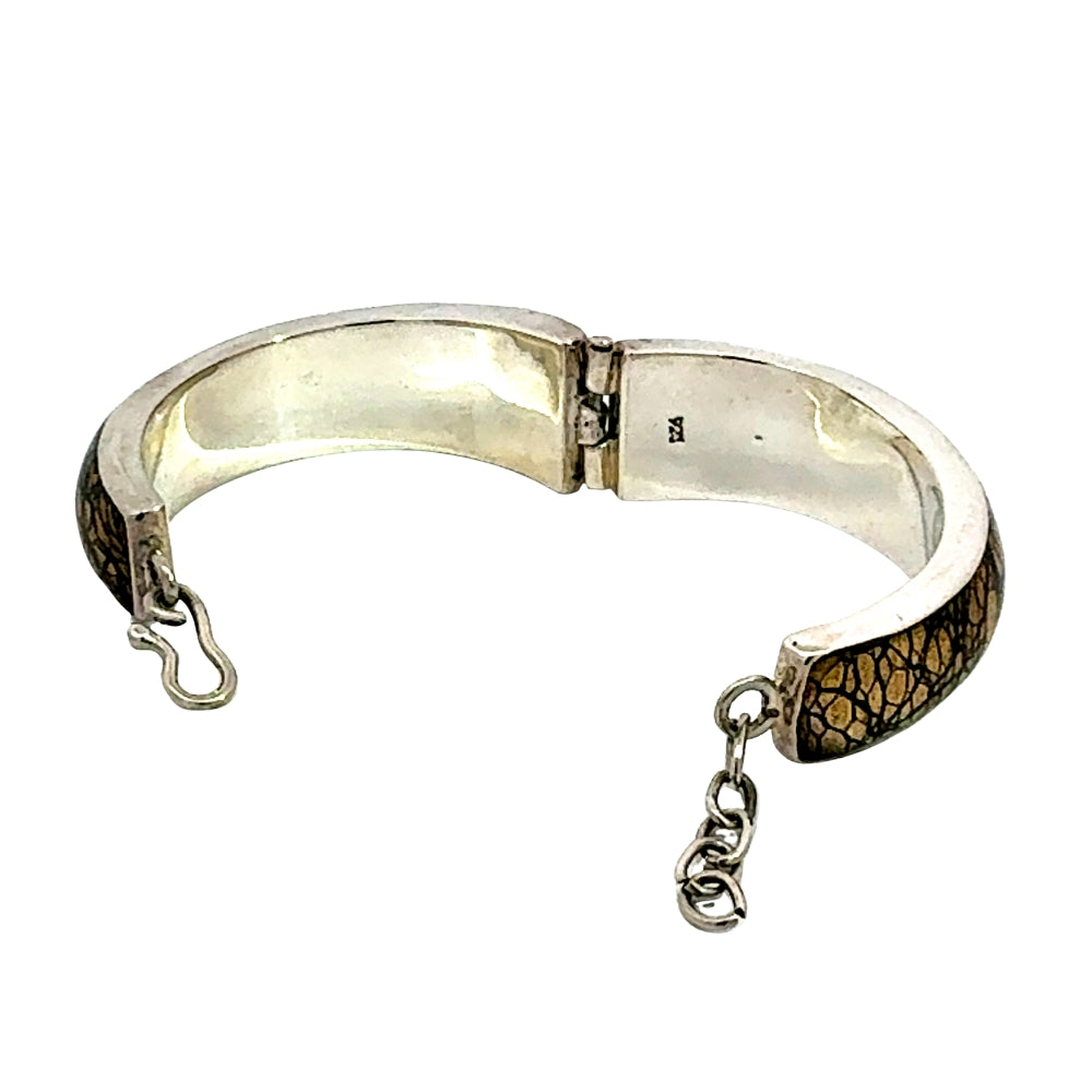 A sterling silver cuff bracelet with textured brown and gold crackled enamel inlays on the outer sides, featuring a lobster clasp and an adjustable hanging chain.