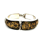 A silver-toned cuff bracelet featuring two large, curved rectangular panels with a textured black and gold crackle or web-like pattern, shown on a plain white background.